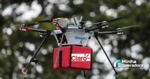 Drone carregando um pacote com o logotipo da Claro