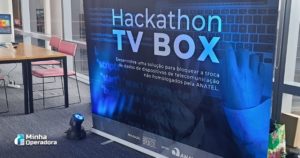 Banner do evento Hackathon TV Box, realizado com apoio da Anatel. O texto no banner convida os participantes a desenvolverem soluções para bloquear a troca de dados de dispositivos de telecomunicação não homologados.