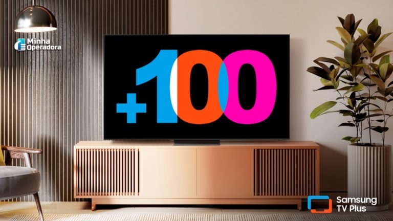 Imagem de uma sala moderna com uma TV Samsung exibindo o número '+100' em destaque, celebrando a marca de 100 canais gratuitos do Samsung TV Plus. O logotipo do Samsung TV Plus está visível no canto inferior direito da tela, reforçando a promoção do serviço de streaming gratuito disponível nas Smart TVs da Samsung.